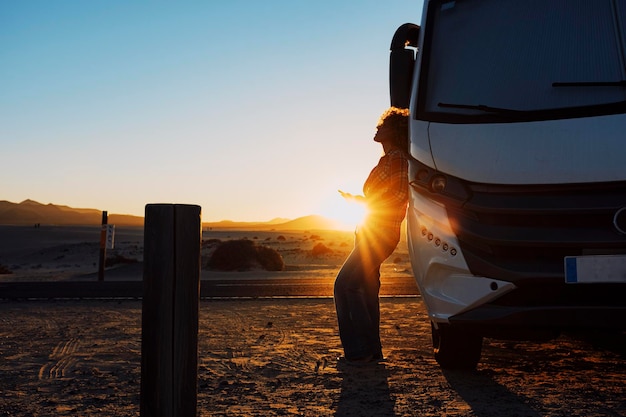 Glücks- und Freiheitsleben mit Frau gegen Wohnmobil und goldener Sonnenuntergang im Hintergrund