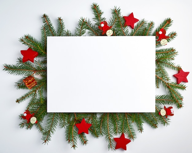 Glückwunschweihnachtshintergrund mit einem leeren weißen Blatt und grünen Niederlassungen der Fichte