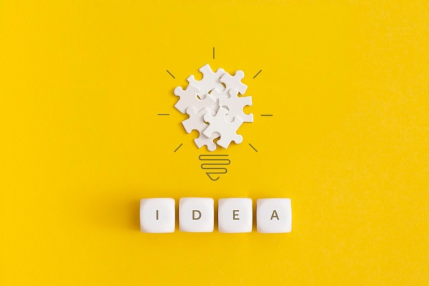 Glühbirne aus Puzzles auf gelbem Hintergrund Inspiration und kreatives Ideenkonzept Draufsicht mit Kopierbereich Flache Lay-Komposition