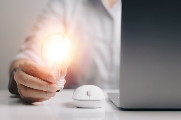 Glühbirne bei der Verwendung eines Laptops neue Ideen mit einem innovativen und kreativen Konzept