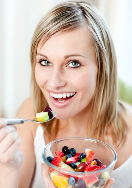 Foto glühende frau, die einen fruchtsalat isst