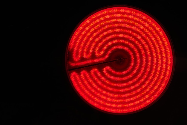 Glühender Brenner der elektrischen Kochplatte auf schwarzem Hintergrund