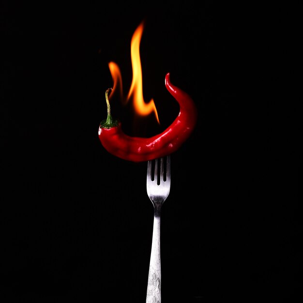 glühender Chili in Flammen auf einer Gabel