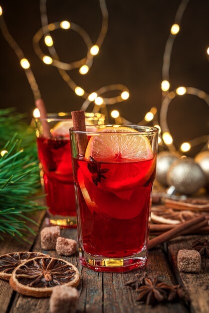 Glühwein auf dem Hintergrund von Tannenzweigen und Weihnachtsbeleuchtung. Winterwärmendes Getränk. Selektiver Fokus.