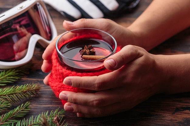 Glühwein in der Frau übergibt gemütliche Hauptkonzeptbestandteilwintersportschutzbrillenskihandschuhe