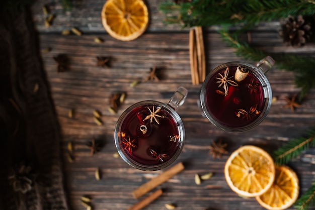 Glühwein in Glasgläsern mit Orangenscheiben, Zimtstangen und Gewürzen mit Weihnachtsdekor. Der Blick von oben