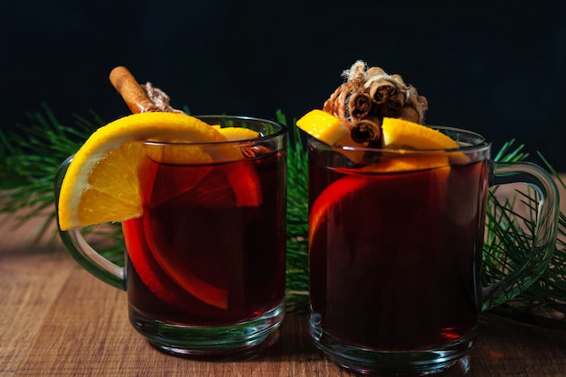 Glühwein mit aromatischen Gewürzen und Orangenstücken auf Holzuntergrund