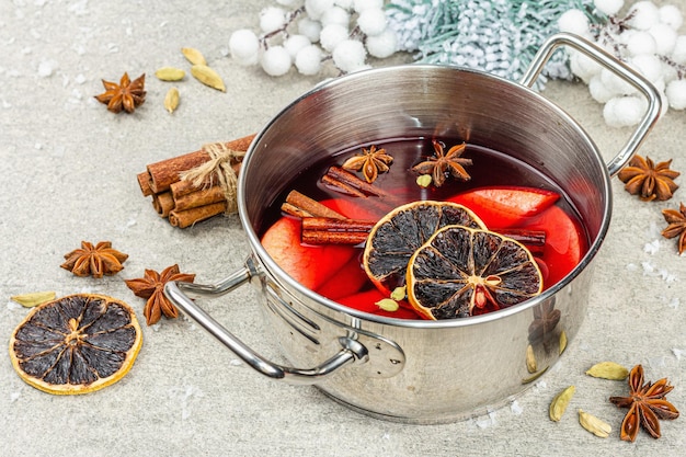 Glühwein mit Gewürzen in einem Topf mit traditionellem Weihnachtsdekor. Heißgetränk im festlichen Hintergrund