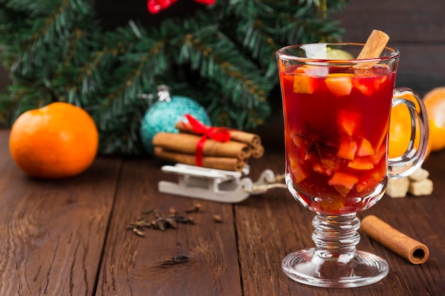 Glühwein mit Zitrusfrüchten im Glas auf dunkler Holzoberfläche