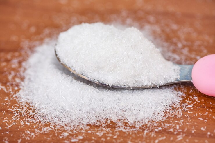 Foto glutamato monosódico en la cuchara y el fondo de la mesa de madera, msg para condimentar alimentos
