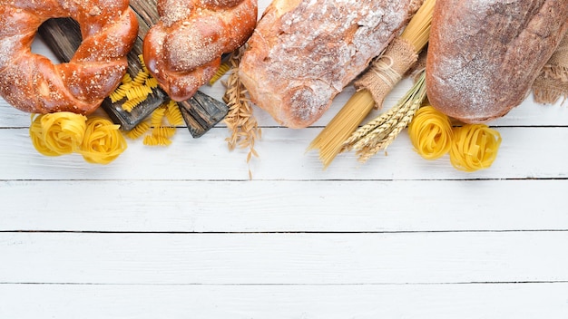 Glutenfreie Lebensmittel Verschiedene Nudeln, Brot, Snacks und Mehl auf weißem Holzhintergrund Draufsicht Freier Platz für Ihren Text