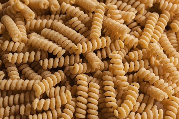 Glutenfreie Maismehlnudeln Tapete Spirale rohe Makkaroni aus Mais- und Reismehl, die sich auf dem Drehteller drehen, Nahaufnahme, Draufsicht, ungekochte Nudeln, die Vollformat-Lebensmittelhintergrund drehen Fusilli Bucati Corti