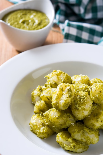 Gnocchi mit Pesto-Sauce in Teller auf Holztisch