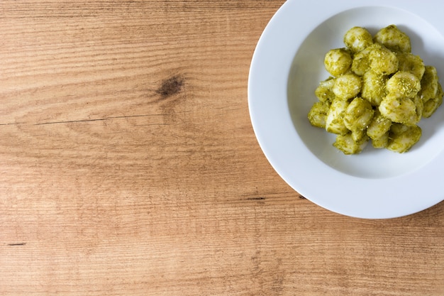 Gnocchi mit Pesto-Sauce in Teller auf Holztisch