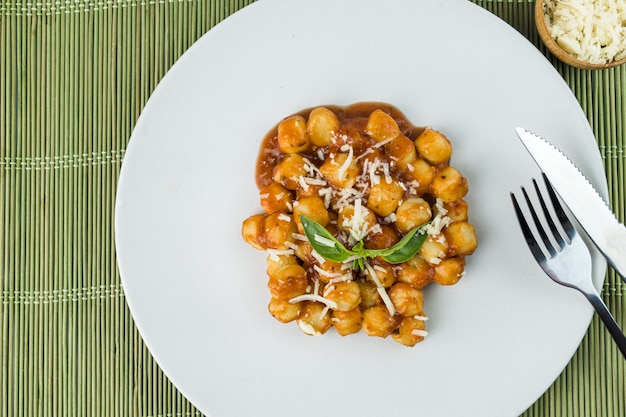 Gnocchi mit Saftsauce mit geriebenem Käse und Basilikum auf dem Teller serviert Nahaufnahme Selektiver Fokus