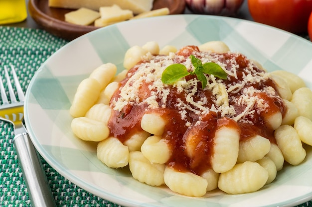 Gnocchi de pasta italiana en un plato con salsa de tomate, albahaca y queso parmesano.