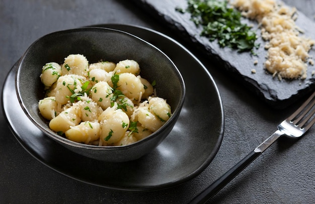 Gnocchi de patata italiana cocinada casera tradicional con perejil de mantequilla y queso parmesano sobre fondo de madera blanca