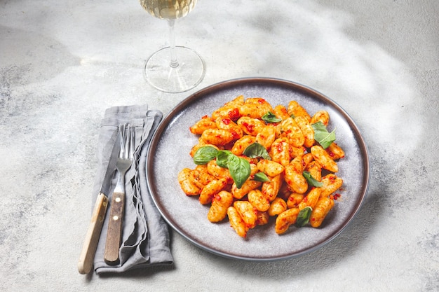 Gnocchi de patata tradicional italiana con salsa de tomate y albahaca fresca sobre placa gris mármol procedencia