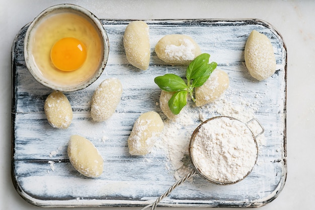 Foto gnocci de patata italiano tradicional decorado con hojas de albahaca, huevos, harina. vista superior. lay flat