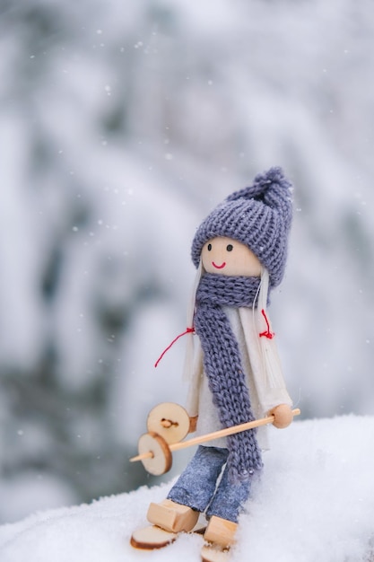 Foto gnomo de anjo em cachecol e chapéu de malha esquiando no ramo de abeto nevado brinquedo de elfo em esquis na paisagem de neve