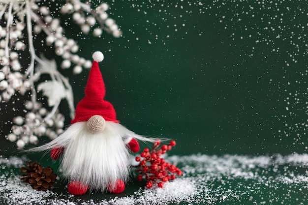 Gnomo de Natal escandinavo com bagas de inverno em fundo verde escuro Cartão de saudação de ano novo