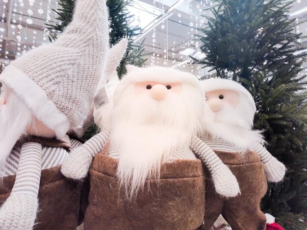 Gnomos navideños de felpa con barba blanca se paran en el vestíbulo del centro comercial debajo del árbol de Navidad