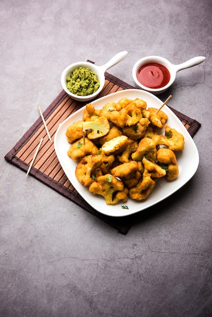 Gobi pakora ou Phoolgobi pakoda feito com couve-flor fresca mergulhada em massa de grão de bico e depois frita em óleo. servido com ketchup de tomate e chutney de hortelã. foco seletivo