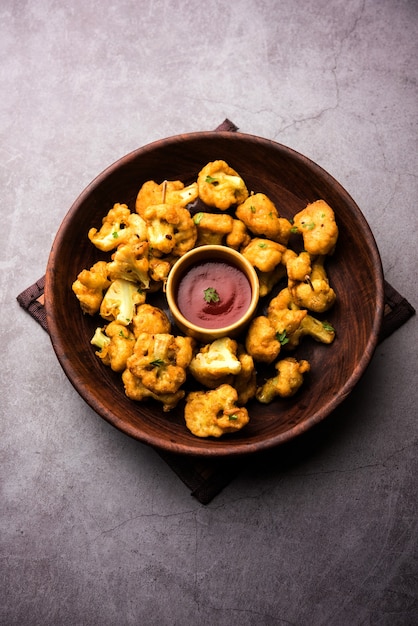 Gobi pakora ou Phoolgobi pakoda feito com couve-flor fresca mergulhada em massa de grão de bico e depois frita em óleo. servido com ketchup de tomate e chutney de hortelã. foco seletivo