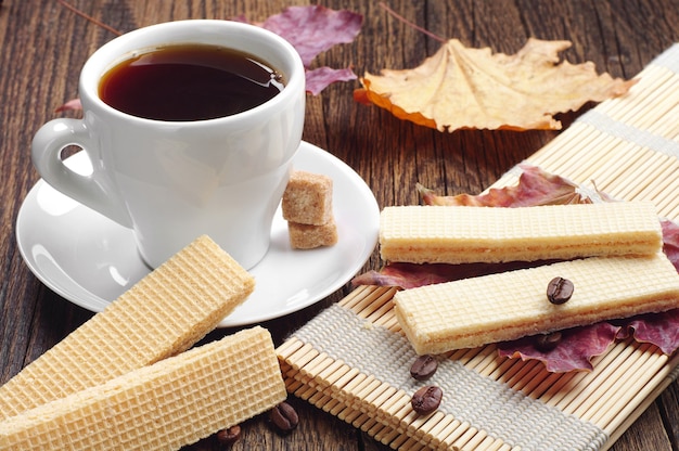 Gofre dulce y taza de café en la mesa de madera