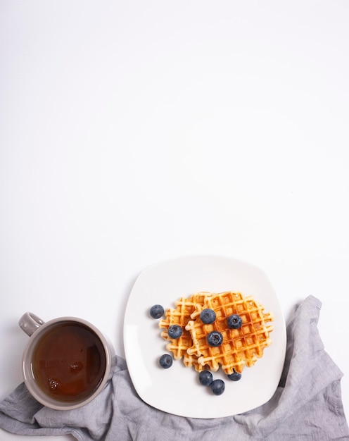 gofres con arándanos en un plato y una taza de café copia espacio