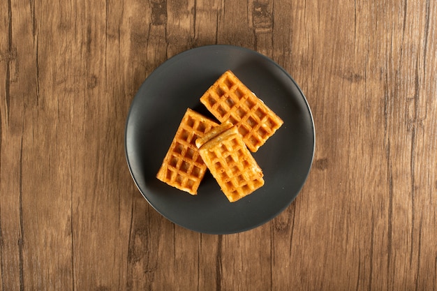 Gofres belgas en un plato sobre una mesa de madera. Vista superior