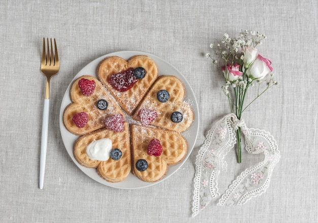 Gofres caseros de corazón belga con salsa de fresas y bayas con flores