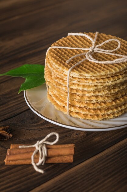 Gofres caseros con crema de caramelo y canela en rama sobre una mesa de madera. Tartas caseras con especias.