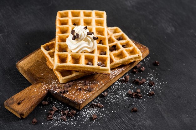 Gofres caseros irritables con crema en el fondo de madera negra