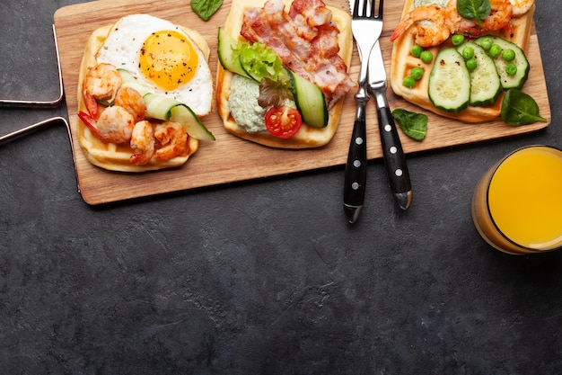 Gofres de desayuno con huevos fritos salmón pepino y gambas