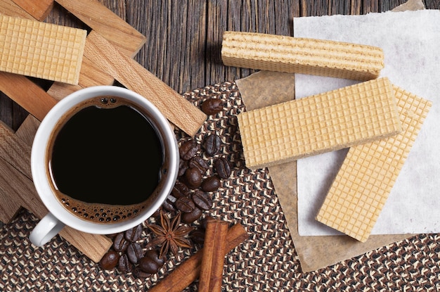 Gofres dulces y una taza de café caliente para el desayuno en la mesa de madera oscura.