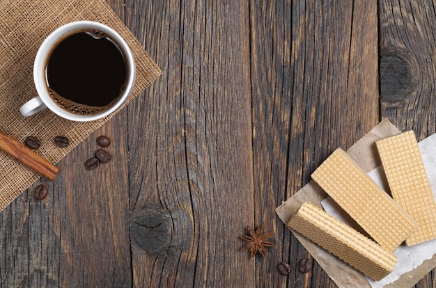 Gofres dulces y una taza de café caliente para el desayuno en la mesa de madera rústica, espacio para texto.