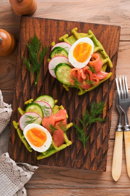 Gofres salados Desayuno gofres verdes ajo silvestre o espinacas con huevo tomate salmón en plato de madera para el desayuno sobre fondo de madera vieja Cena ligera almuerzo o desayuno Vista superior Maqueta