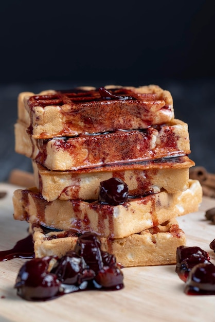 Gofres suaves con mermelada de cereza roja en una tabla para servir