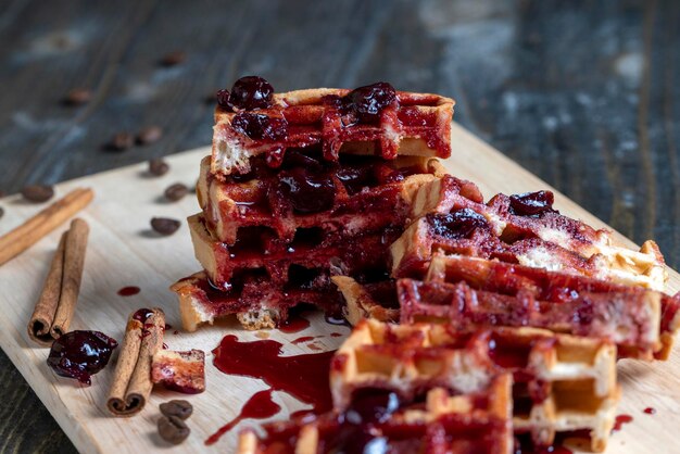 Gofres suaves con mermelada de cereza roja en una tabla para servir