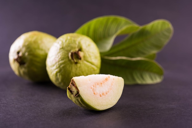 Goiaba verde fresca também conhecida como Amrood em hindi e Peru em Marathi, servida em uma cesta inteira ou em fatias sobre um fundo colorido. Foco seletivo