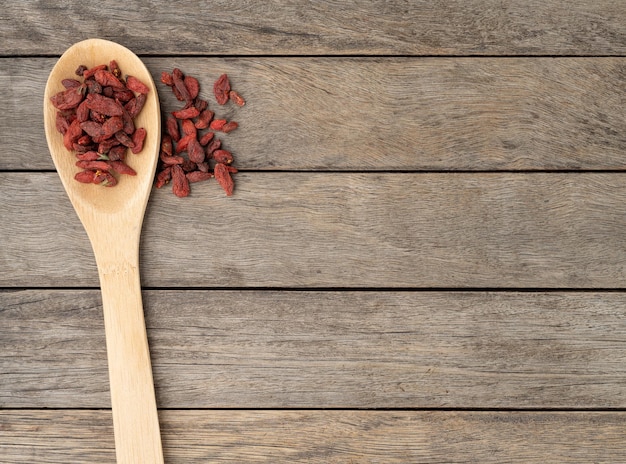 Goji-Beere in einem Löffel über Holztisch mit Kopienraum.