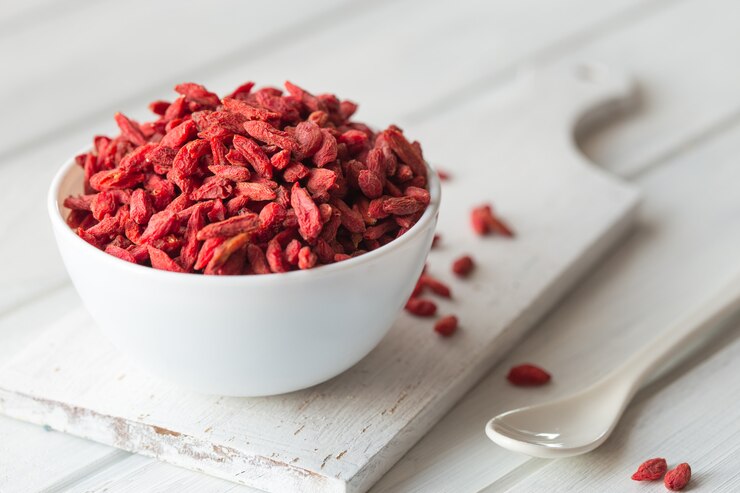Goji em tigela na mesa de madeira.