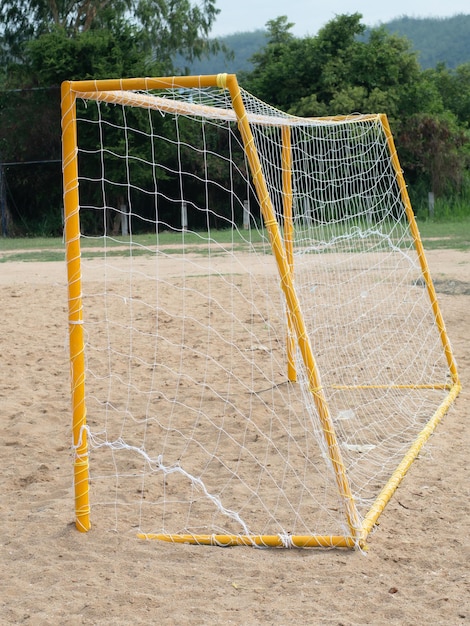 Gol de fútbol amarillo en campo de arena en zona rural