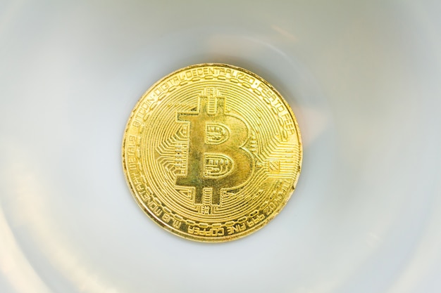 Gold-Bitcoin-Münze auf weißem seramic Hintergrund.