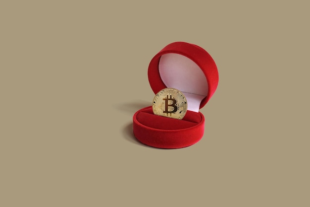 Gold-Bitcoin-Münze in einer roten Geschenkbox auf pastellbraunem Hintergrund