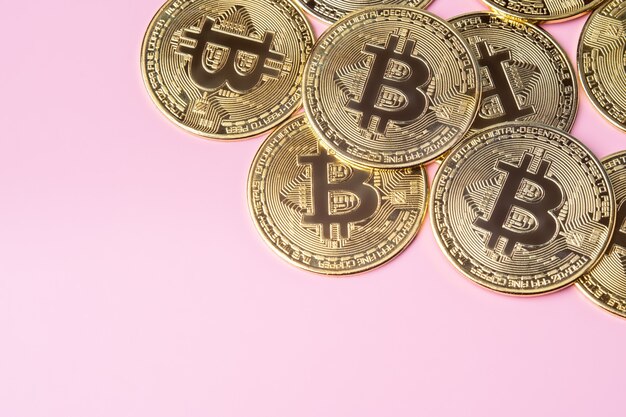 Foto gold-bitcoins auf rosa hintergrund. kryptowährung und geld.