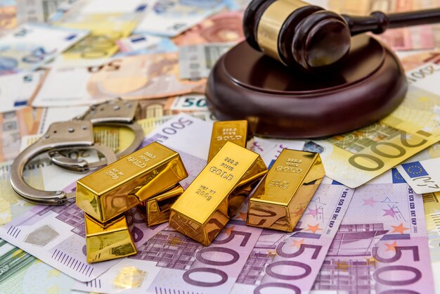 Goldbarren mit richterhammer und handschellen an euro-banknoten