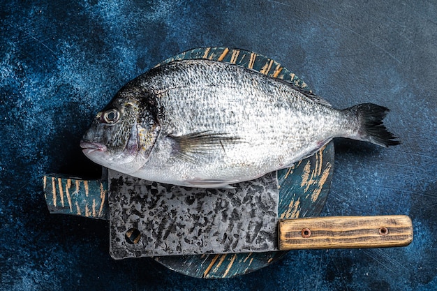 Goldbrasse oder Dorado-Fisch auf dem Fischmarkt-Schneidebrett Blauer Hintergrund Ansicht von oben