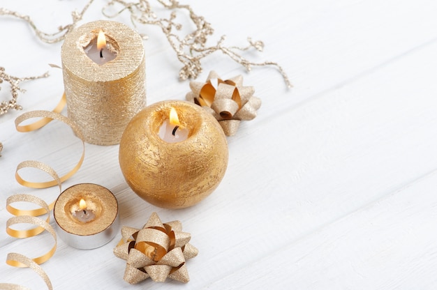 Golden beleuchtete Aromakerzen und Weihnachtsspielzeug auf rustikalem Holzhintergrund